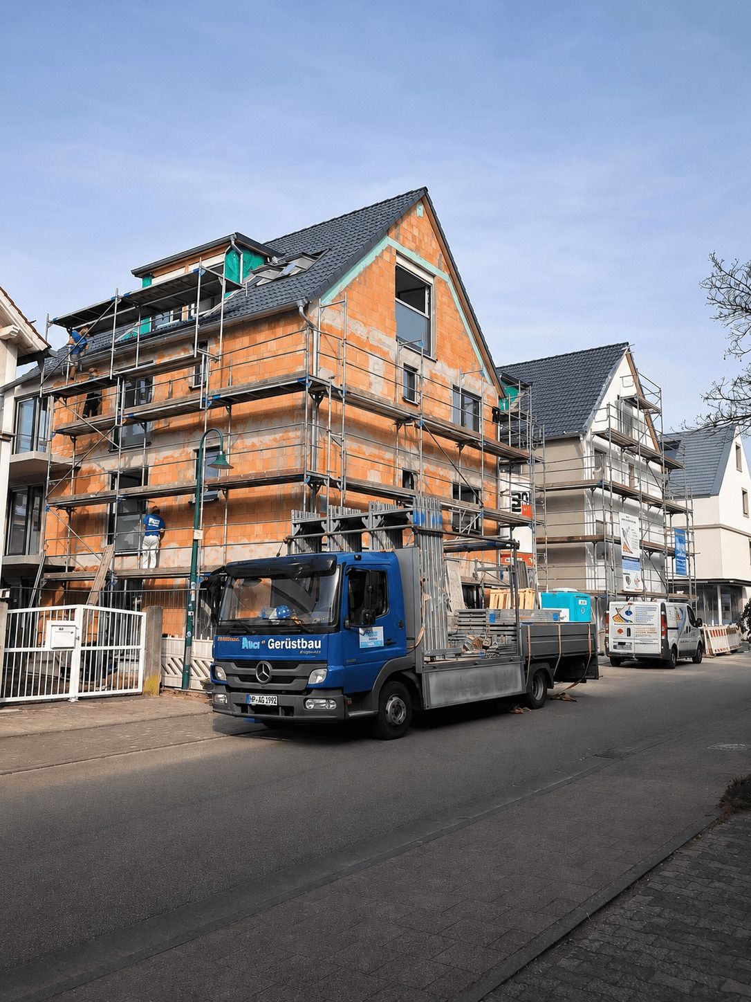 Eingerüsteter Neubau mit Dachfanggerüst und AVCI-Transporter