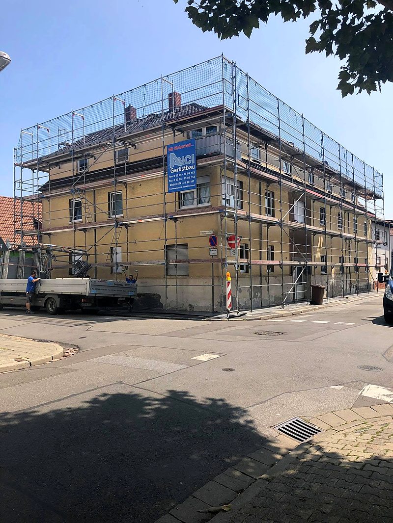 Komplett eingerüstetes Wohnhaus mit Schutznetz über der Traufe